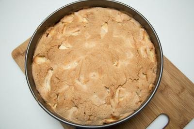 Sharlotka Apple Cake in a baking pan standing on a cutting board