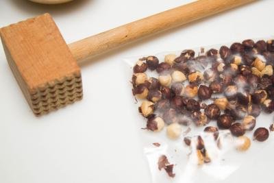 Hazelnuts in a ziplock bag with a meat tenderizer next to the bag