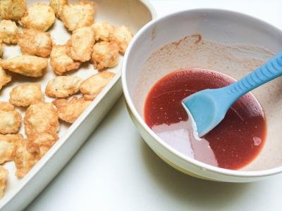 baking pan with chicken bites and a bowl with the sauce next to it