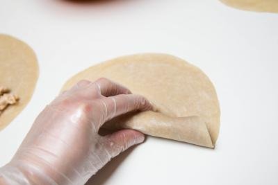 Uncooked tortilla with filling being rolled in a roll