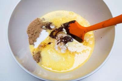 chocolate mixture in a bowl with eggs, brown and white sugar added into it