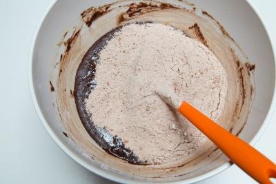 Flour and cocoa mixture added into the chocolate mixture and being mixed together with a spatula