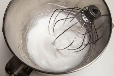 Egg whites and sugar being beat in a KitchenAid mixer