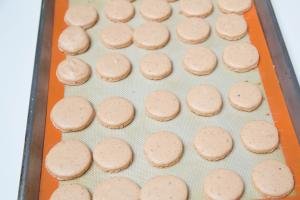 Macarons on a baking pan lined with a silicon mat