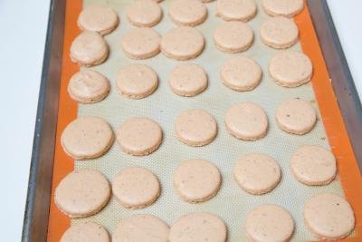 Macarons on a baking pan lined with a silicon mat