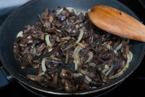onions and mushrooms being sautéed on a skillet