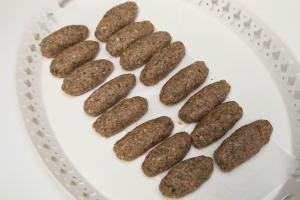 Beef Kofte Kebab rolled out into long ovals and placed in rows on a plate