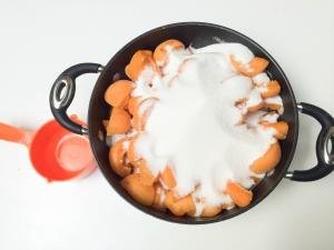 Halved apricots with sugar on top in a large pot