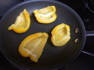 Yellow bell pepper being roasted on a pan