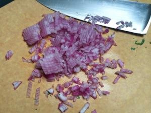 Purple onion being dice on a cutting board