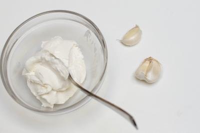 Cream cheese in a bowl with 3 garlic cloves next to it