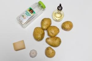 Ingredients on table including; potatoes, garlic, parmesan, oil and garlic salt