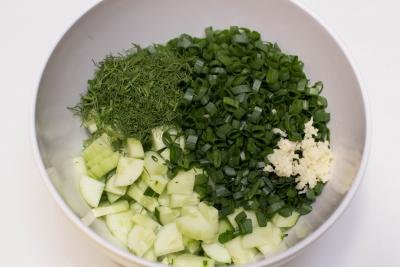 Cucumbers, green onions, minced garlic, and dill in a bowl