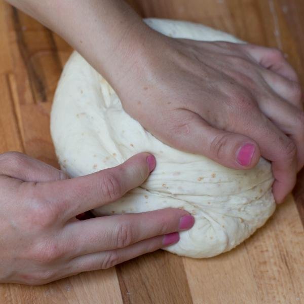 Dough being kneaded on a floured cutting board