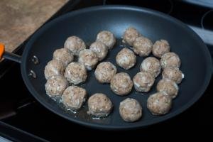 Meatballs being fried on a skillet