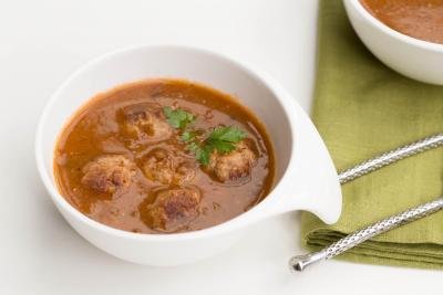 Tomato Lentil Soup with Meatballs in a bowl with a spoon next to it