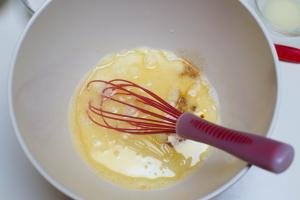 Eggs, milk, and vanilla extract and oil all placed into one large mixing bowl with a whisk