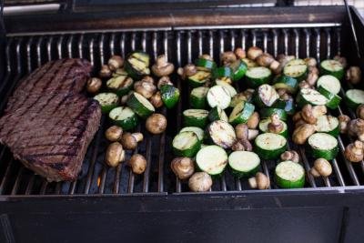 Seasoned zucchini and Mushrooms on a grill with a steak next to them
