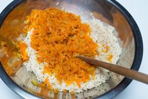 Sautéed onions and carrots added to a bowl with rice