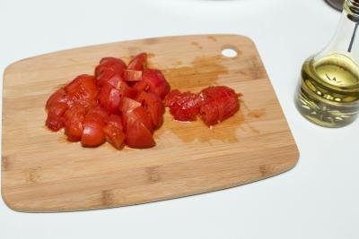 Peeled tomatoes being diced on a cutting board