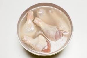 Sugar, salt, and lemon juice dissolved in a bowl with water with chicken drumsticks in the water