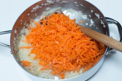 Shredded carrots added to the large skillet with onions