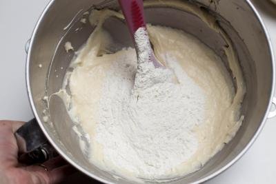 Flour mixture being added into the cake batter in the mixing bowl and being combined with a spatula