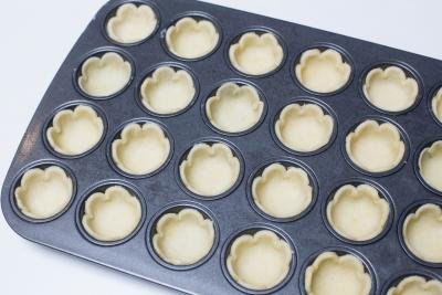 Cut out cookies placed into a mini cupcake baking pan