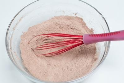 Sifted flour and cocoa being mixed together with a whisk