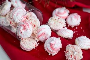 Peppermint Meringue Cookies in a tall vase like container that is layer sideways on a table napkin