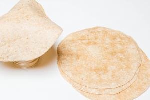 A pile of tortillas and one tortilla on top of the bottom of the jar