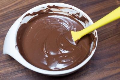 Melted chocolate in a bowl being stirred with a spatula