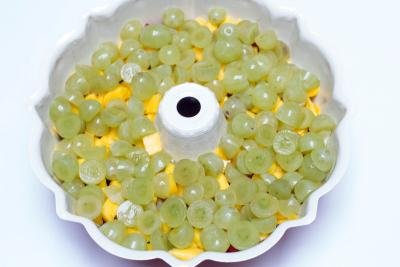 Halved green grapes placed on top of the sliced mangos in the Jello cake mold