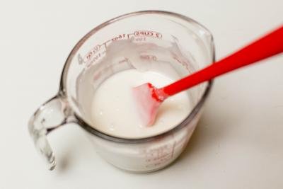 Milk and powdered sugar combined in a measuring cup using a spatula