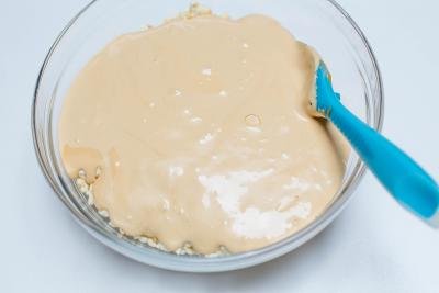 Cream being stirred into the cake crumble in a bowl with a spatula
