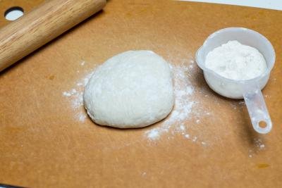 pizza dough on a cutting floured cutting board
