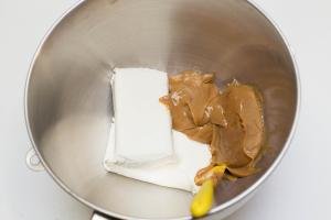 2 packets of cream cheese and dulce de leche placed into a mixing bowl with a spatula