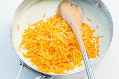 Cheddar cheese being mixed into the deep skillet with the milk mixture
