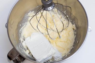 Cream cheese added into a mixing bowl with butter and sugar