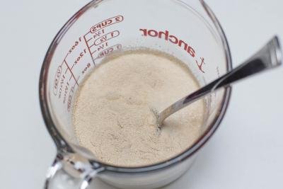 Yeast, milk and sugar in a measuring cup with a spoon in the cup