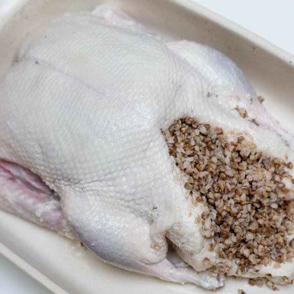Seasoned duck in a ceramic baking pan filled with buckwheat