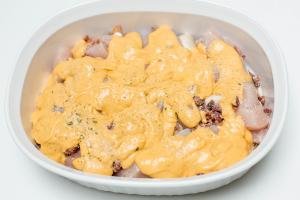 Campbell's cheesy sauce spread on top of the chicken, mushrooms and bacon in the ceramic baking dish
