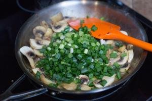 Diced green onions added into the skillet with mushrooms and butter