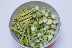 Halved brussel sprouts and asparagus in a large bowl
