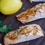 Baked Salmon on a cutting board with lemons besides the fillets