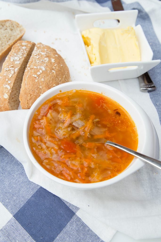 Cabbage Soup in a bowl with bread and butter next to it