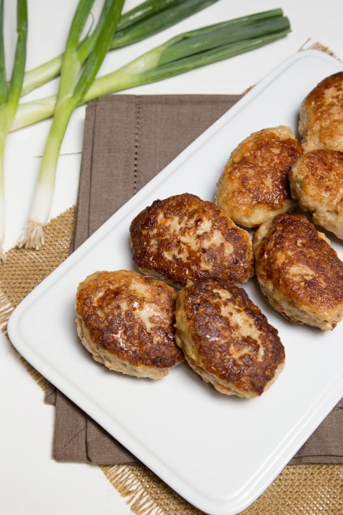 Chicken Kotleti on a plate with green onions next to the plate