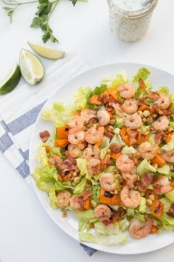 Shrimp Lettuce Salad on a large plate, with a jar of ranch dressing next to it and limes