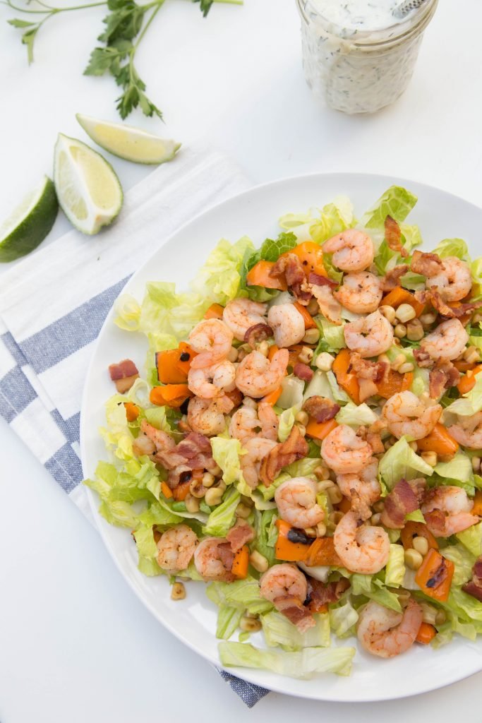 Shrimp Lettuce Salad on a large plate, with a jar of ranch dressing next to it and limes