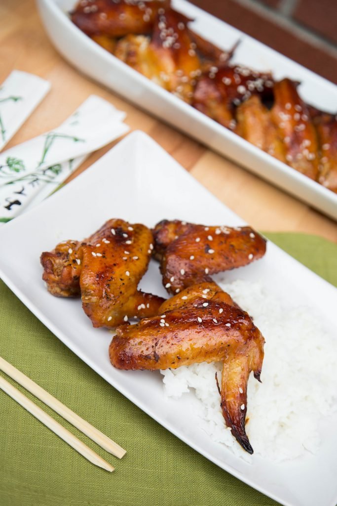 Easy Glazed Chicken Wings on rice on a plate with chopsticks next to the plate